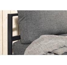 Detaljvy av en trädgårdssoffa med grå dynor och filt