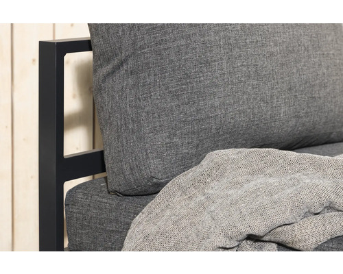 Detaljvy av en trädgårdssoffa med grå dynor och filt