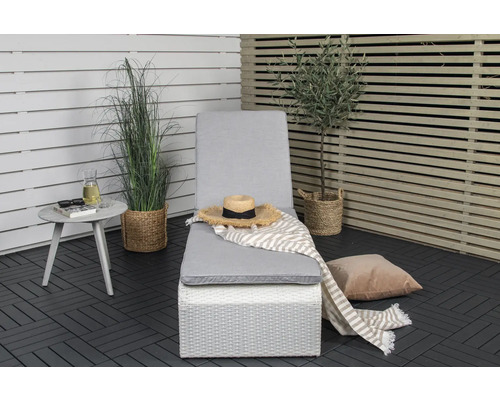 Scen med en trädgårdssäng, ett sidobord och dekorativa växter på en terrass.