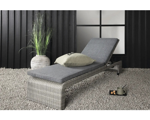 Trädgårdsscen med en grå solstol med dyna, en kudde och en krukväxt