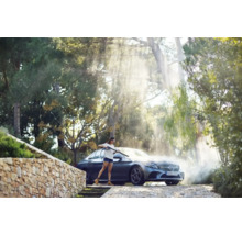 Kvinna rengör bil med högtryckstvätt utomhus.