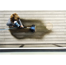 En person rengör en träterrass med en terrasstvätt.