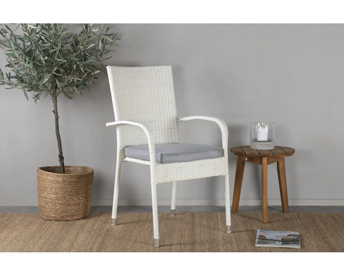 Flätad karmstol med sittdyna bredvid bord och växt