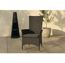 Flätad trädgårdsfåtölj med armstöd och sittdyna bredvid en dekorativ kolonn och en krukväxt.