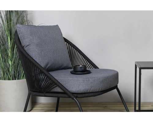 Trädgårdsscen med rottingfåtölj med dynor och sidobord