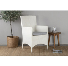 Flätad trädgårdsfåtölj med sittdyna bredvid sidobord, krukväxt och tidning