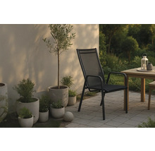 Scen med trädgårdsstol, bord och växter utomhus.