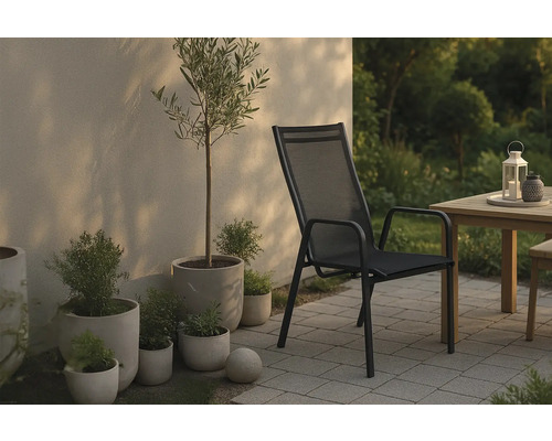 Scen med trädgårdsstol, bord och växter utomhus.