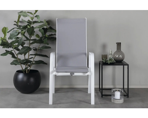 Trädgårdsscen med vit trädgårdsstol, krukväxt och sidobord