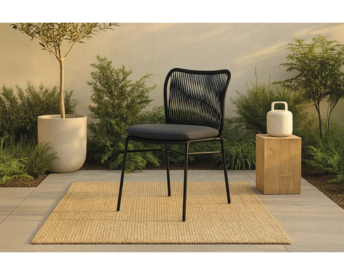 Scen med en utomhusstol med ryggstöd av rep, en växt i en kruka och en utomhuslampa på en pall