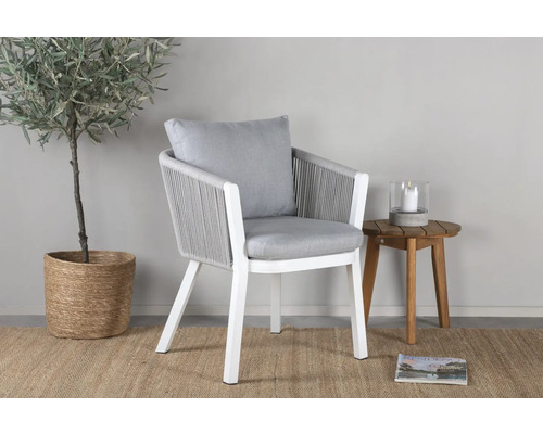 Trädgårdsscen med vit fåtölj, sidobord, krukväxt och matta