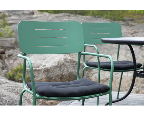 Två gröna metallstolar med svarta sittdynor och ett runt bord för trädgården.