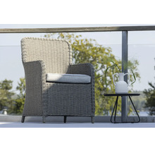 Flätad stol med dyna och sidobord med blomvas på en terrass