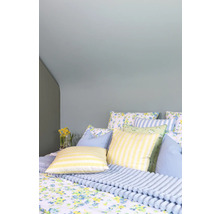 Mysigt sovrum med blommigt sänglinne, randiga kuddar och ett ribbat överkast