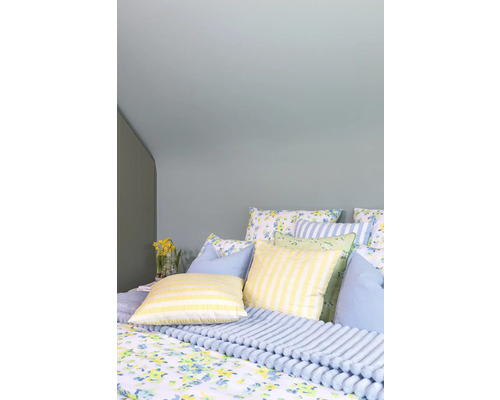 Mysigt sovrum med blommiga kuddar och filtar för en ljus och organiserad atmosfär.