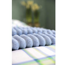 Prydnadskudde med noppmönster på sängkläder