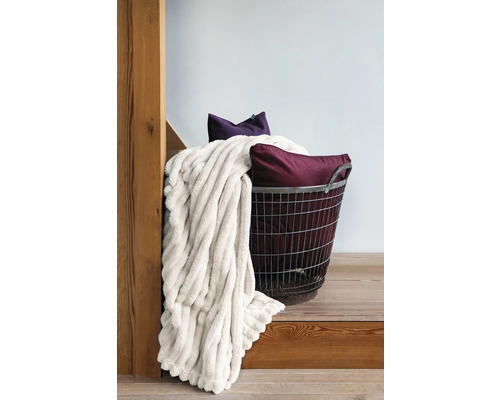 Trådkorg med filt och kuddar på en trätrappa