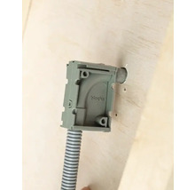 Ytmonterad kapsling med korrugerat rör på en vägg