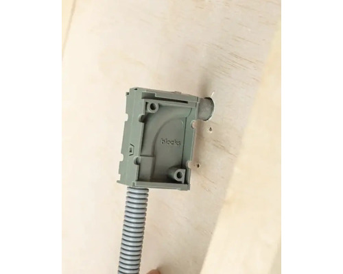 Ytmonterad kapsling med korrugerat rör på en vägg