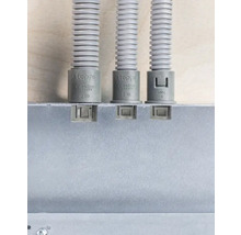 Tre elektriska skyddsrör med matchande ändstycken fästa på en vägg.