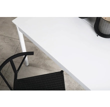 Detalj av ett vitt bord med en svart rottingstol