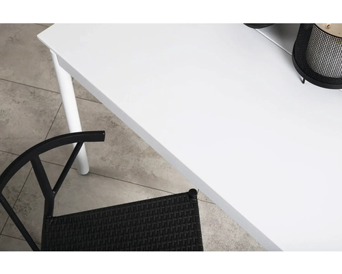 Detalj av ett vitt bord med en svart rottingstol