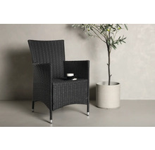 Flätad stol med armstöd och dryckeshållare bredvid en krukväxt.