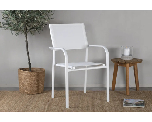 Vit metallträdgårdsstol med armstöd bredvid ett litet träbord