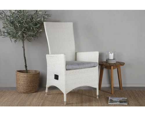 Vit rottingfåtölj med armstöd och grå kudde bredvid sidobord