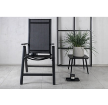 Trädgårdsscen med en trädgårdsstol med armstöd och ett litet bord med krukväxt