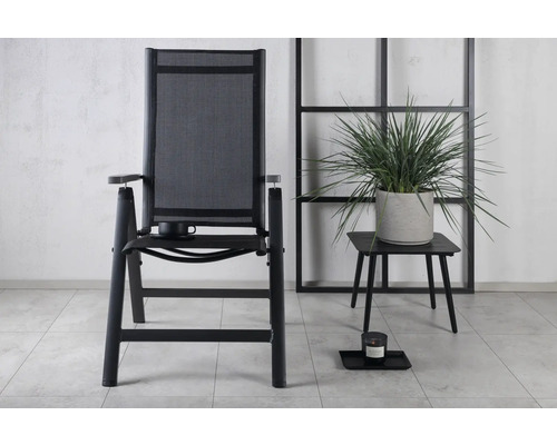 Trädgårdsscen med en trädgårdsstol med armstöd och ett litet bord med krukväxt