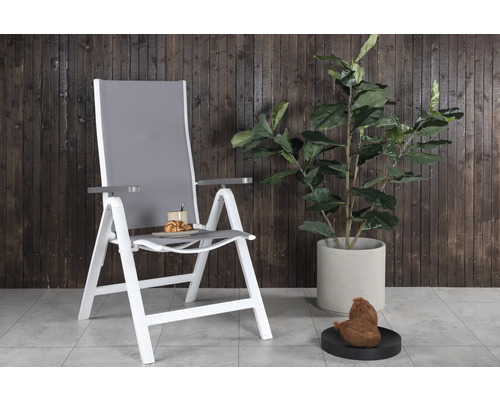 Trädgårdsscen med grå och vit hopfällbar stol bredvid krukväxt