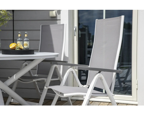 Trädgårdsscen med trädgårdsbord, två trädgårdsstolar och drycker.