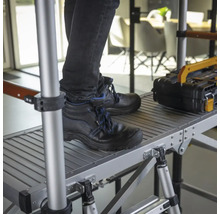 Person med arbetsskor står på en ställning med verktygslåda