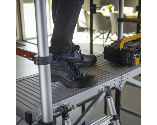 Person med arbetsskor står på en ställning med verktygslåda