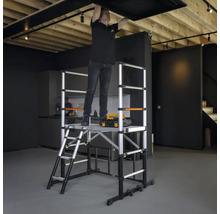 Man monterar taklampa på en rullställning av aluminium i ett rum.