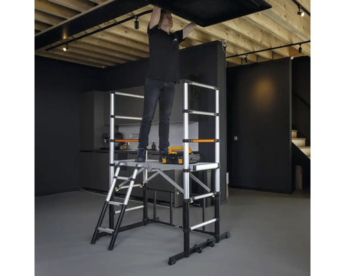 Man monterar taklampa på en rullställning av aluminium i ett rum.