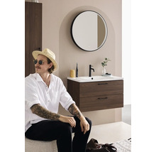 Modernt badrum med tvättställsskåp, rund spegel och en man med hatt