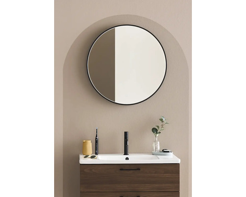 Badrum med tvättställsskåp, armatur, rund spegel och dekoration