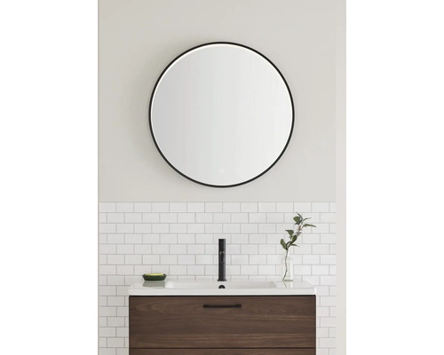 Badrum med rund spegel, handfat och blandare