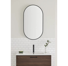 Modernt badrum med tvättställ, armatur och oval spegel med belysning