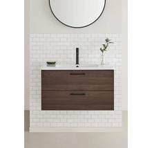 Badrum med tvättställsskåp, handfat och spegel på en kakelvägg