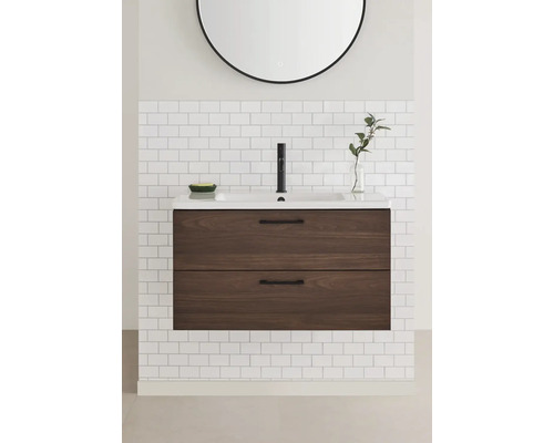 Badrum med tvättställsskåp, handfat och spegel på en kakelvägg