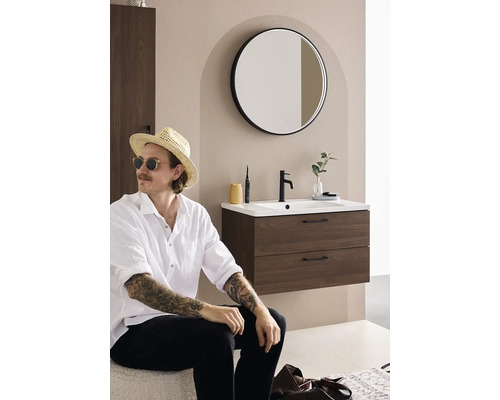 Modernt badrum med tvättställsskåp, rund spegel och stilfull dekoration