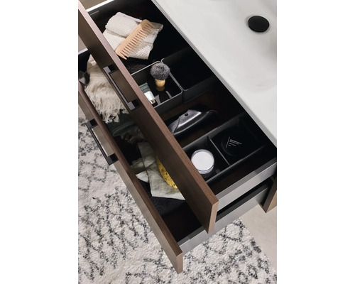 Öppna badrumslådor med diverse badrumsartiklar som en rakborste, handdukar och hudvårdsprodukter