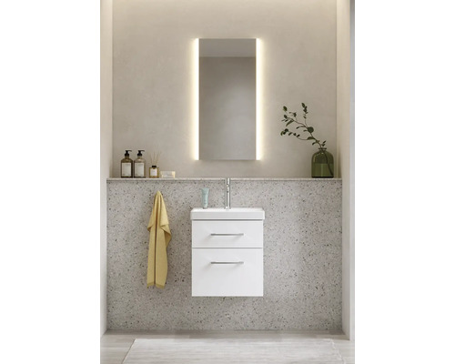 Badrum med tvättställsskåp, tvättställ, spegel med belysning och dekorationsartiklar