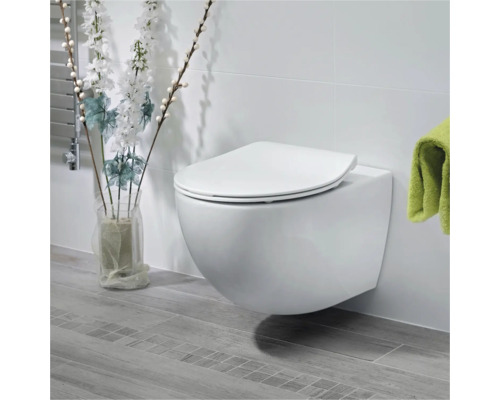 Vägghängd toalettstol med sits i ett ljust badrum.