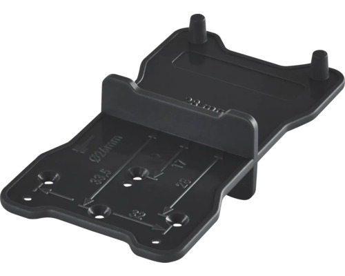 Svart borrmall och markeringsmall i plast för möbelmontering med millimetermarkeringar.