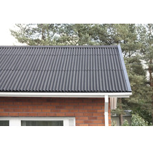 Närbild av ett tak med korrugerad plåt på en tegelbyggnad.