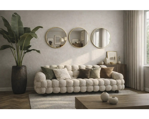 Vardagsrum med stoppad soffa, prydnadskuddar, krukväxt i en kruka och tre runda speglar på väggen.